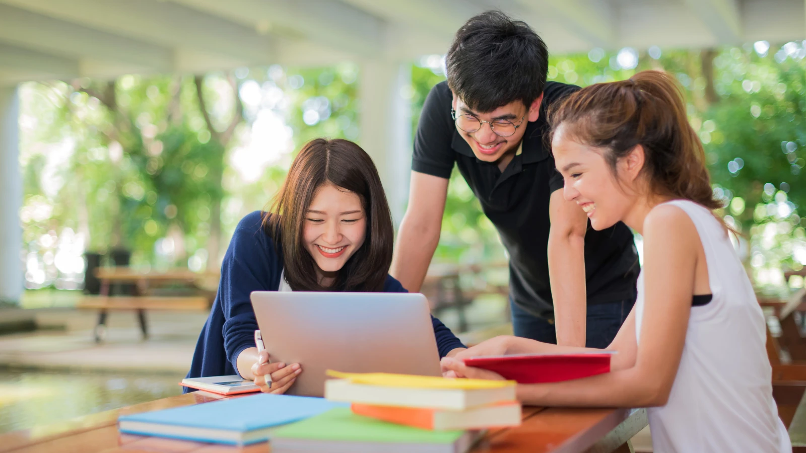 Image of college students gleaming and looking into a laptop 